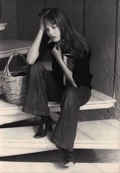 black and white photograph of a woman sitting on steps with a basket in front of her