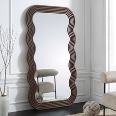 a large mirror sitting on top of a floor next to a chair