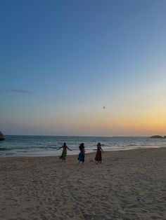 three children are playing on the beach at sunset