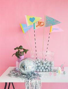 a table topped with lots of balloons and confetti balls next to a pink wall