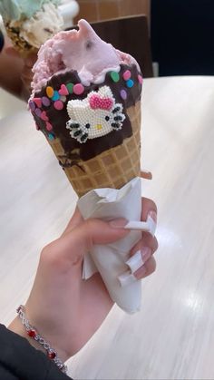 a person holding an ice cream cone with chocolate frosting and sprinkles