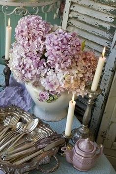 a table topped with lots of silverware next to a vase filled with pink flowers