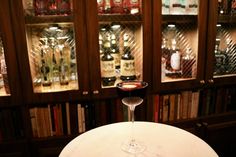 a wine glass sitting on top of a table in front of shelves with liquor bottles