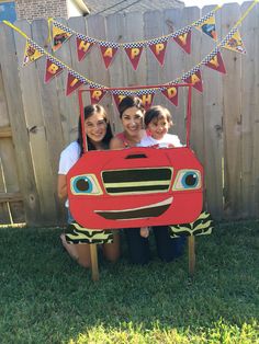 three girls are posing in front of a red truck with decorations on the top and sides