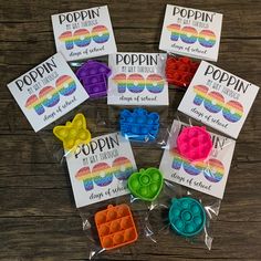 several different colored plastic buttons in bags on a wooden table with labels for poppin's