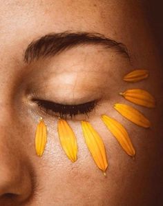 a woman's face with yellow flowers painted on her eyes