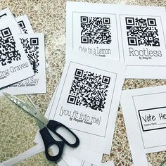 four pieces of paper with qr code designs on them and scissors next to it