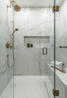 a walk in shower sitting next to a white counter top under a light brown faucet