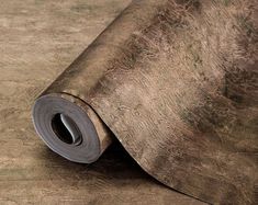 a roll of metallic foil sitting on top of a wooden floor next to a wall