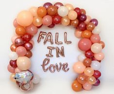 a balloon arch that says fall in love