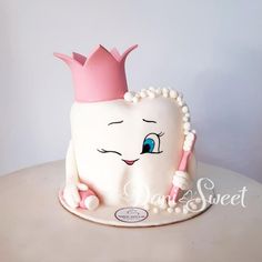 a tooth shaped cake with a pink crown on it's head and pearls around the teeth