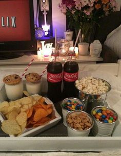 snacks and drinks on a tray in front of a television with candy, milk, chips, and soda