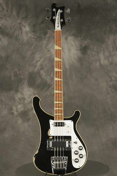 a black and white guitar sitting on top of a gray surface with clouds in the background