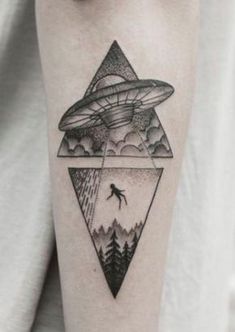 a man's arm with an alien flying over the mountains and trees on it