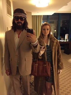 a man in a suit and tie taking a selfie with a woman holding a cell phone