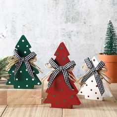 three small wooden christmas trees with bows on them