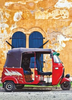 a red three wheeled vehicle parked in front of an old building