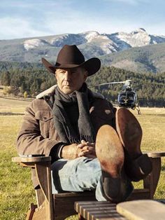 a man wearing a cowboy hat sitting in a chair with his foot on the ground