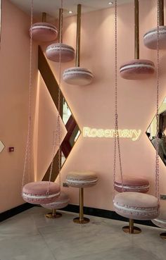 the pink room is decorated with gold and white accents, including round stools that are suspended by chains