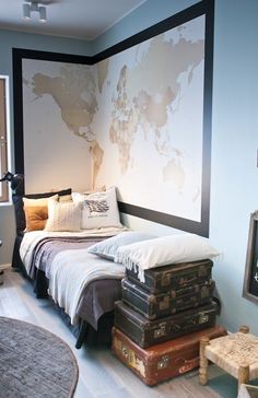 a bed with luggage stacked on top of it next to a wall mounted world map