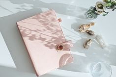 a pink notebook sitting on top of a white table next to flowers and seashells