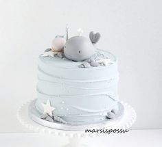 a white cake with blue frosting and a whale on top that is decorated with seashells