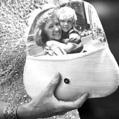 a woman holding a small child in a bag with the reflection of her on it