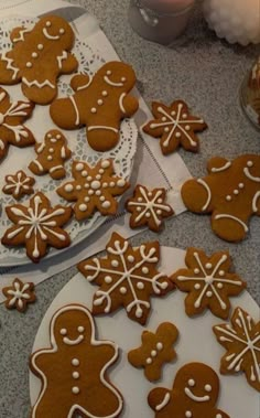 gingerbread cookies decorated with white icing and snowflakes are on a table next to a lit candle