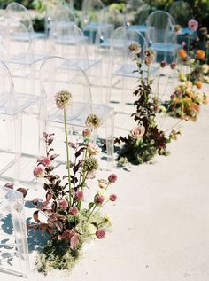 there are many clear chairs with flowers in them