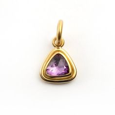 a gold pendant with an amethorate stone in the shape of a triangle