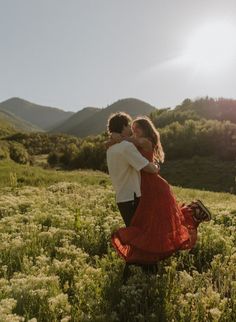 a man and woman hug in the middle of a field