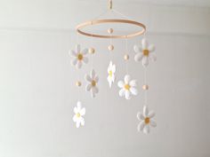 a white and yellow mobile with flowers hanging from it's sides on a wall