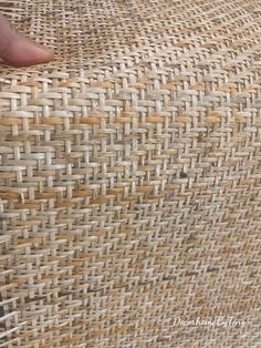 a hand is touching the side of a wicker chair