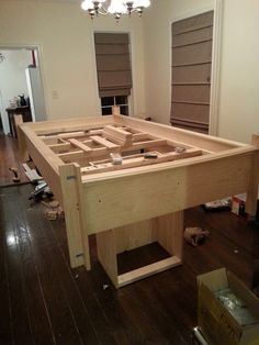 an unfinished bed frame in the middle of a room with hard wood flooring and windows