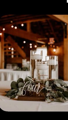 a table with candles and greenery on it in front of a sign that says four