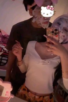 a woman with makeup on taking a selfie in front of a hello kitty mirror