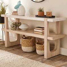 a wooden table with baskets under it and a round mirror on the wall behind it