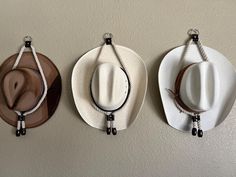 Elevate your space with these beautifully handcrafted cowboy hat hangers, designed for both functionality and style. Made from durable, thick rope with sturdy leather accents, these hangers feature sleek metallic rivets and finely crafted leather beads at the ends, offering a rustic yet elegant way to display your favorite hats. The minimalist design ensures that your hats are the true stars of the show, while the textured rope and leather give a nod to the rugged charm of Western living. Perfect for any cowboy or cowgirl looking to add a touch of rustic flair to their home decor, these hangers not only provide a secure hold for your hats but also act as an eye-catching decorative piece on your wall. Whether you hang one or several together, these hangers make a great gift or a stylish upg Cowboy Hat Hanger, Hat Hangers, Cowboy Hut, Leather Beads, Texas Wall Art, Cowgirl Look, Boy Wall Art, Hat Hanger, Chapeau Cowboy