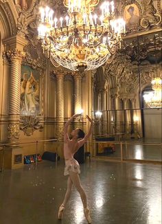 a young ballerina is practicing her moves in the dance hall with chandelier