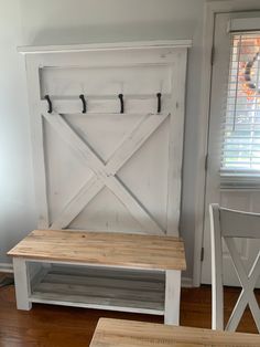 a wooden bench sitting in front of a white barn door with two hooks on it