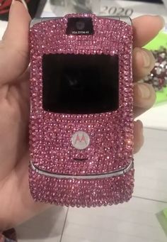 a person holding a pink cell phone with lots of diamonds on it's screen