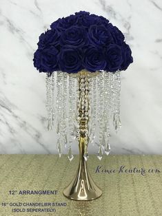 a gold vase filled with purple roses and crystal beads on top of a marble table