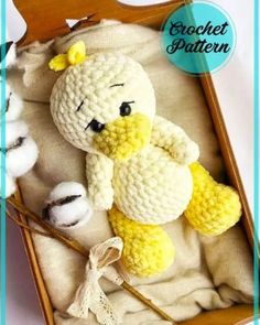 a crocheted stuffed animal in a wooden box with cotton balls on the floor