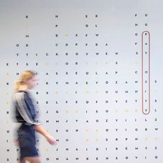 a woman walking past a wall with words on it and a red line in the middle