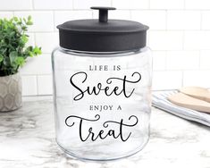 a glass jar with the words life is sweet and enjoy a treat in black lettering