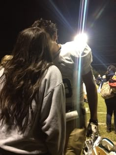 a football player kissing his girlfriend on the sidelines