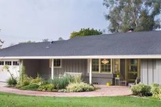 a small house with a large front yard and landscaping around the porch area is shown on a sunny day