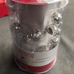 a canister filled with lots of shiny balls on top of a table next to a red box