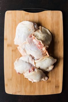 raw chicken sitting on top of a wooden cutting board