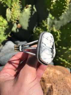 Sterling silver and White Buffalo. Sterling drop accents. Hand-stamped detail. Just under 1 7/8" wide at widest point. Cuff measures 5 3/4" with a flexible 1" gap. Stamped sterling and signed by Navajo artist. White Buffalo, Hand Stamped, Buffalo, Gap, Cuff, Stamp, Sterling Silver, Silver, White